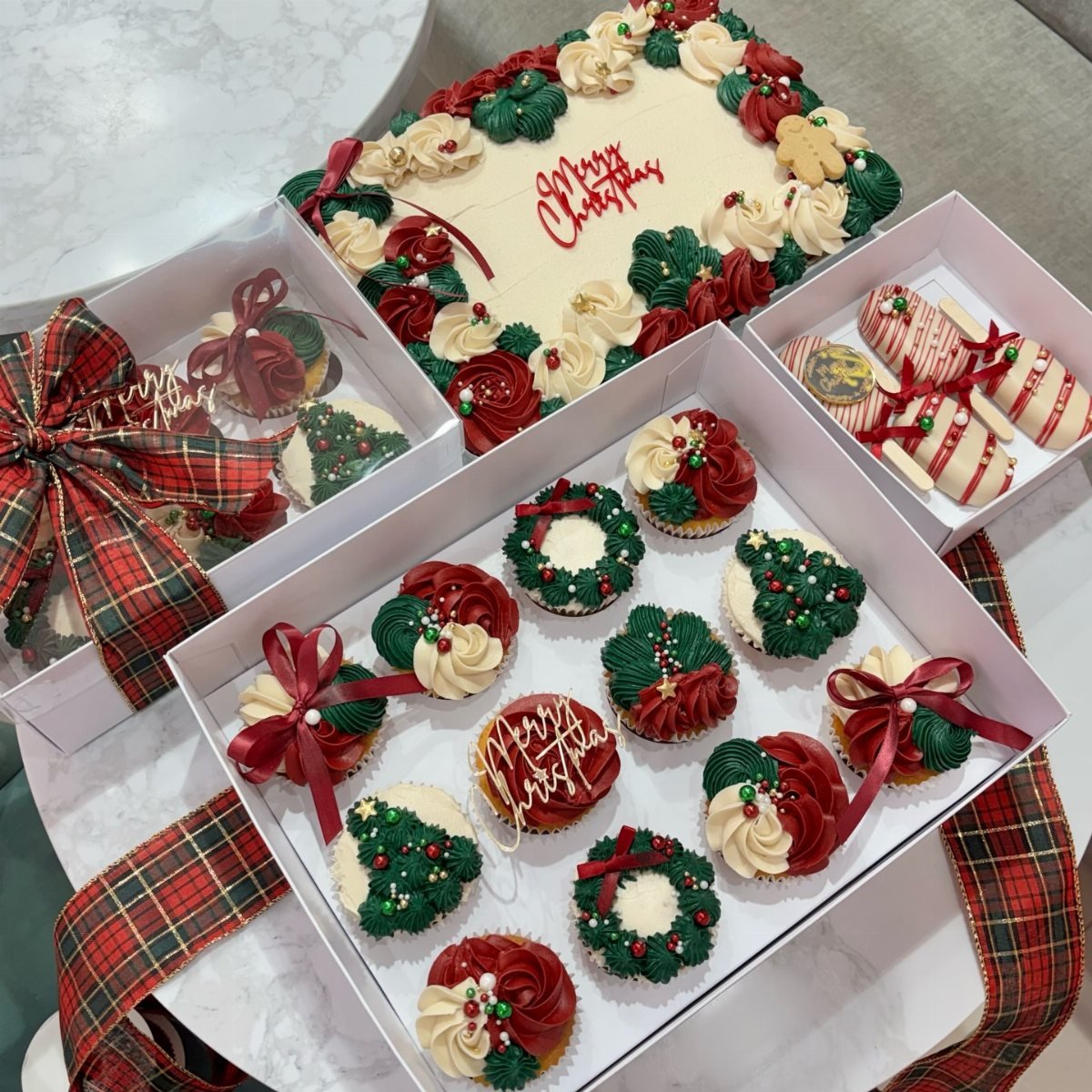 Assorted Christmas cupcakes with red and green frosting in white gift boxes.