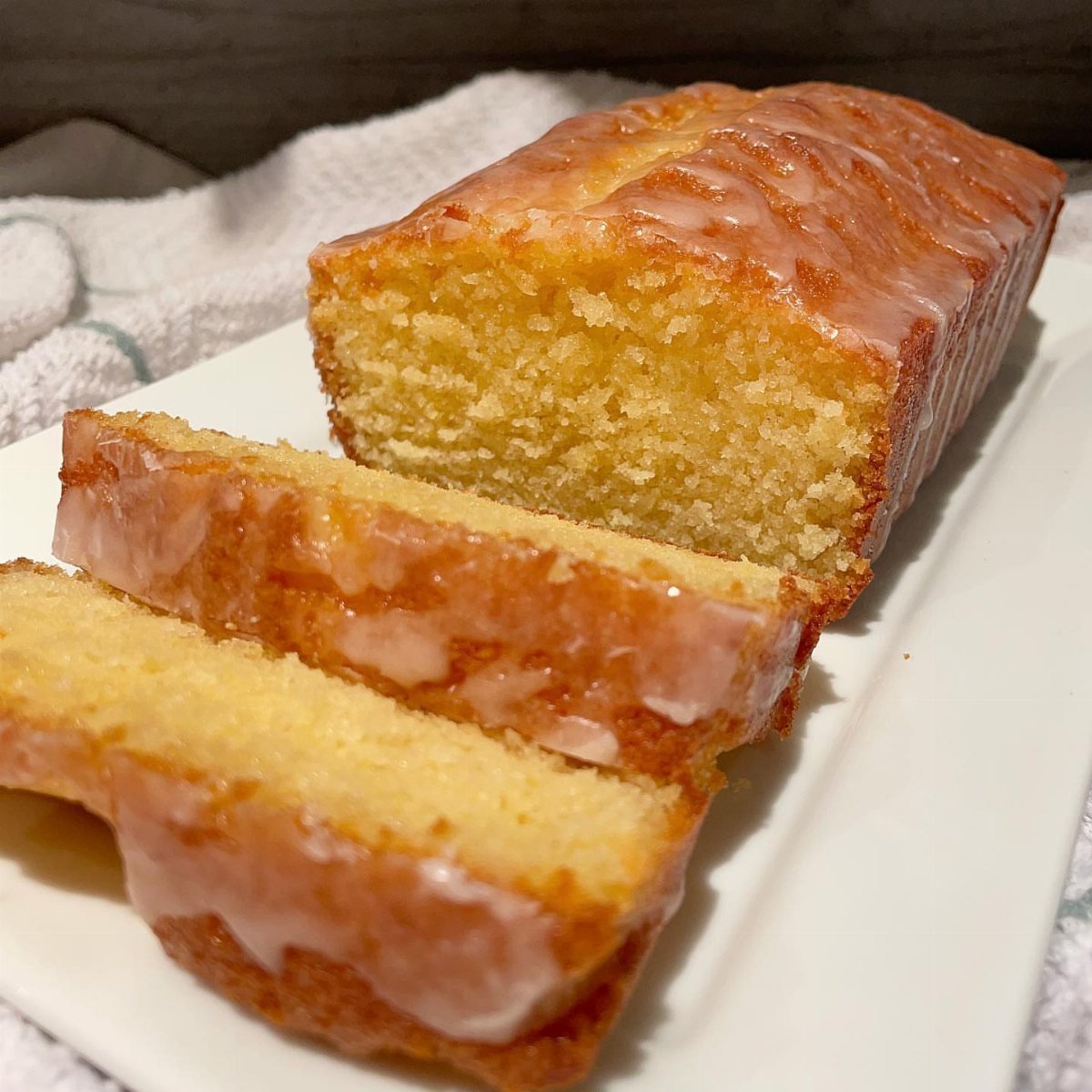 Sliced lemon pound cake with white glaze on a white plate.