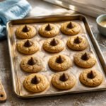 A plate of peanut butter blossoms with chocolate kisses on top.